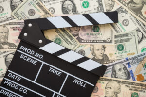 movie clapperboard on pile of cash